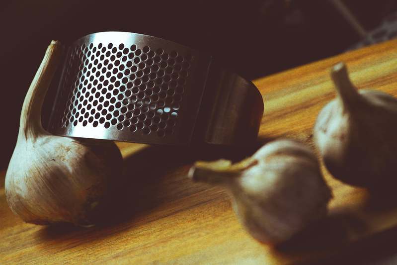 Blogger testing multiple garlic presses side-by-side on a well-lit countertop